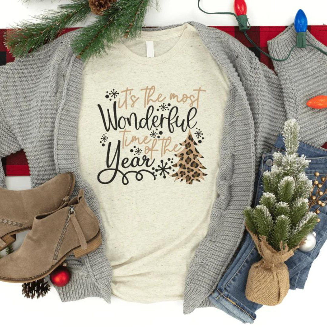 Flat lay of t shirt with gray cardigan, jeans, shoes and Christmas decor. Shirt says It's the most wonderful time of the year.